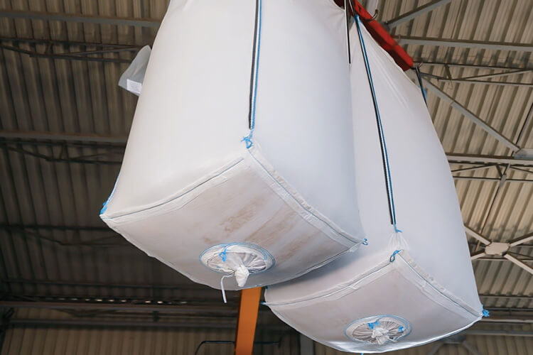 two disposable bulk bags being suspended by a hoist